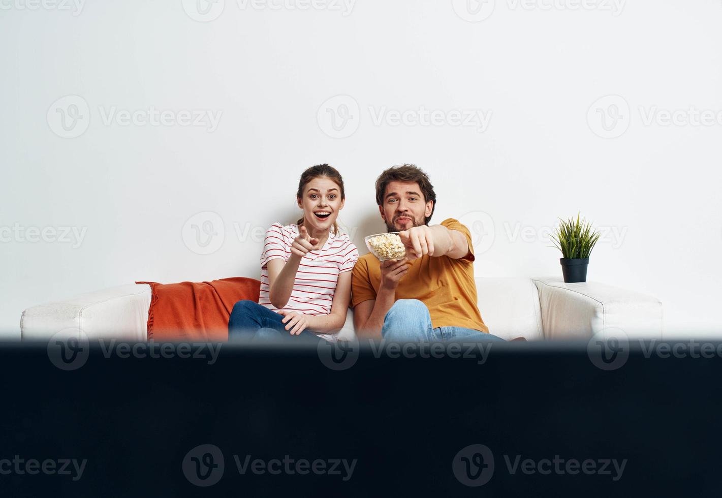 A man and a woman on the couch watching the TV indoors watching the show photo