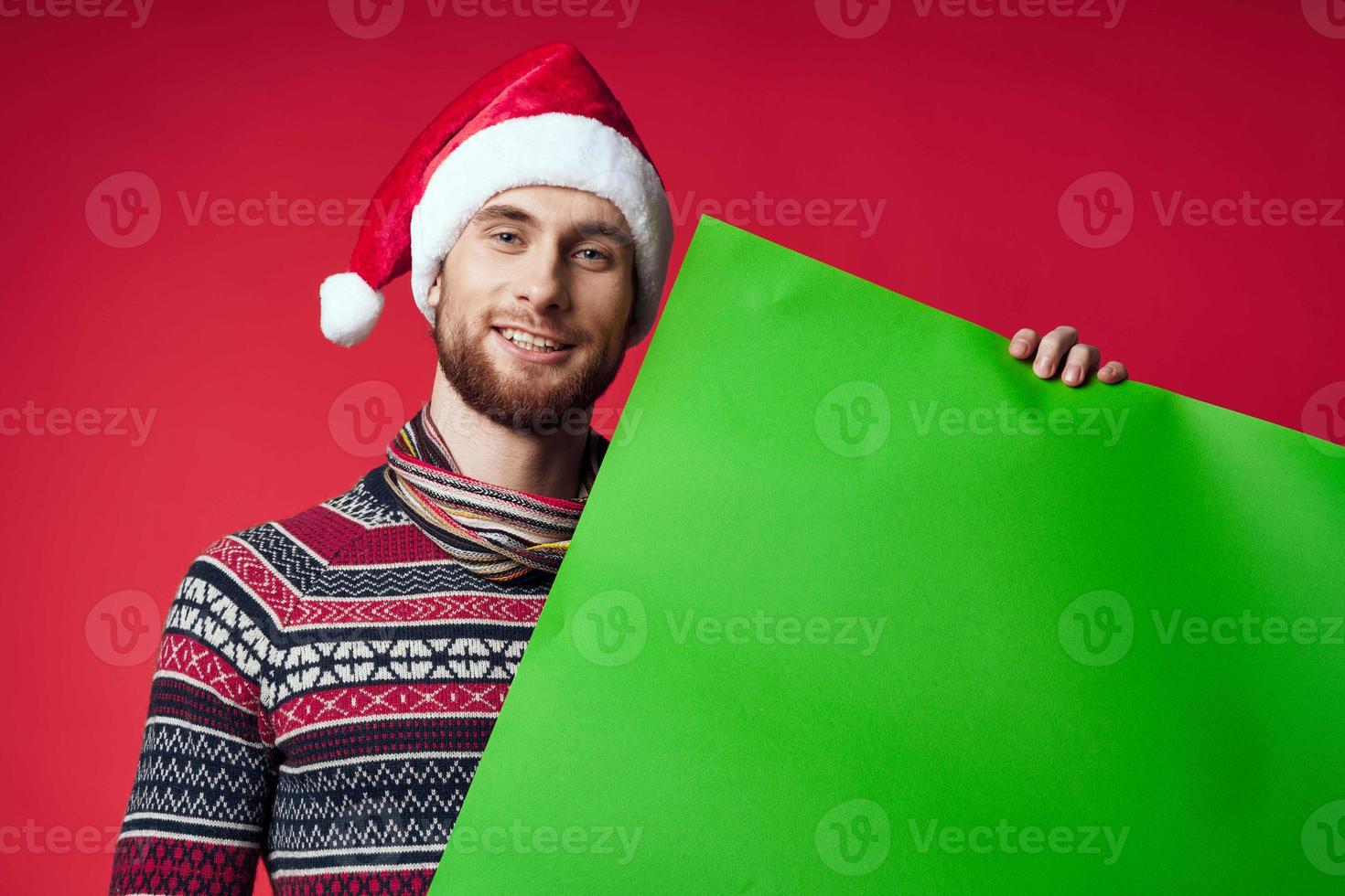 emotional man in a santa hat holding a banner holiday red background photo