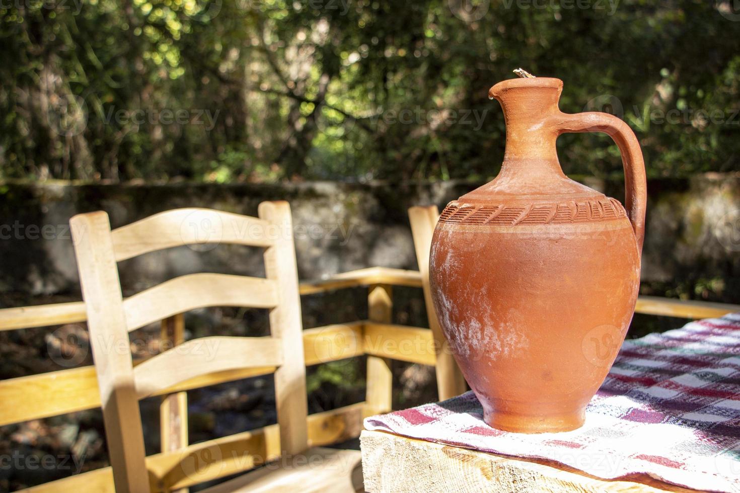 The clay jug on a wooden table in the garden. Traditional handmade clay jug. Vintage style. photo