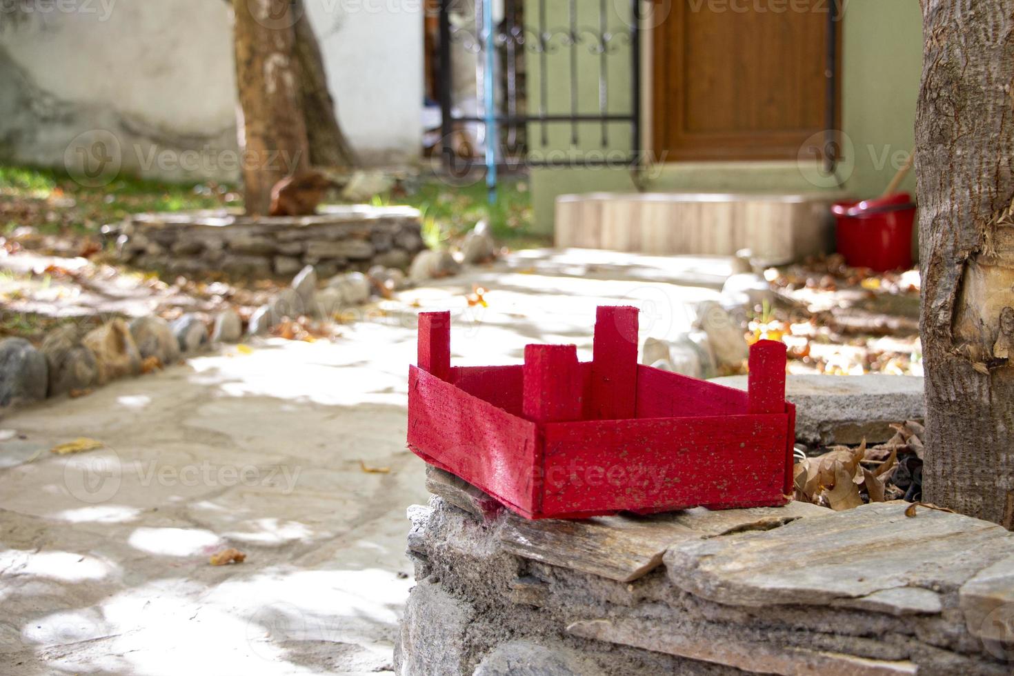 Red wooden basket on a stone in the garden. The red wooden box on a stone wall in the courtyard of the house photo