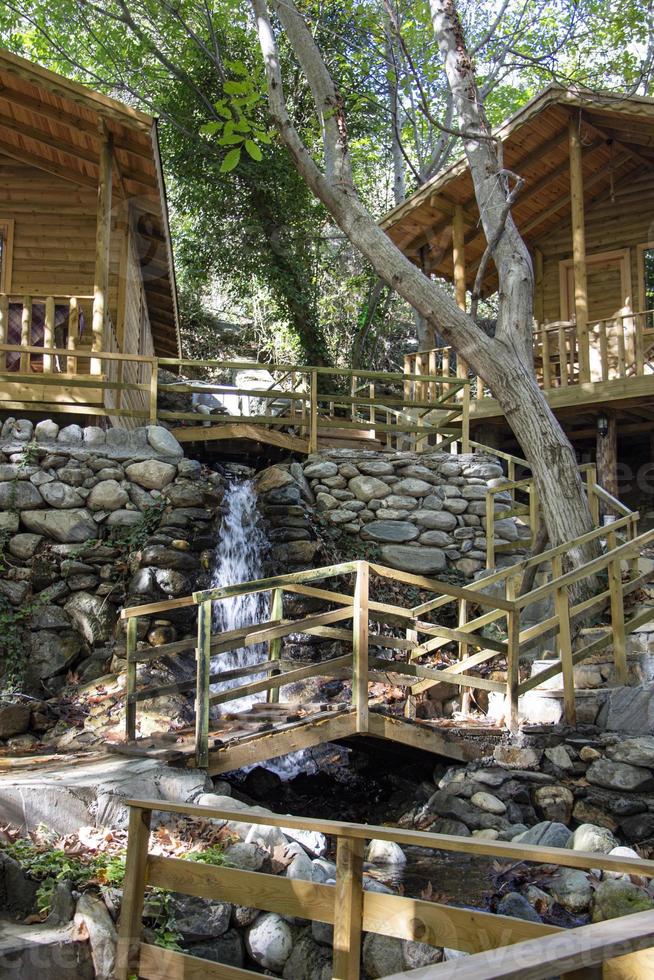 Waterfall in the park. Water cascades down the stairs. Waterfall in the forest with wooden stairs and railings in the mountains photo