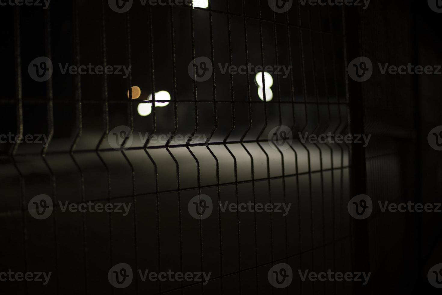 Fence at night. Mesh for protection. Grille on black background. photo
