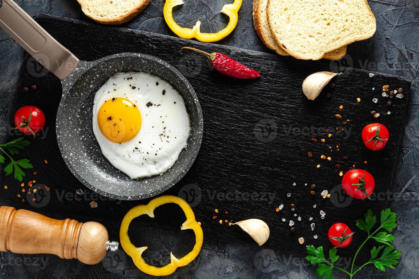 Fried eggs in a frying pan with fresh vegetables and spices. Concept for menu and advertising. photo