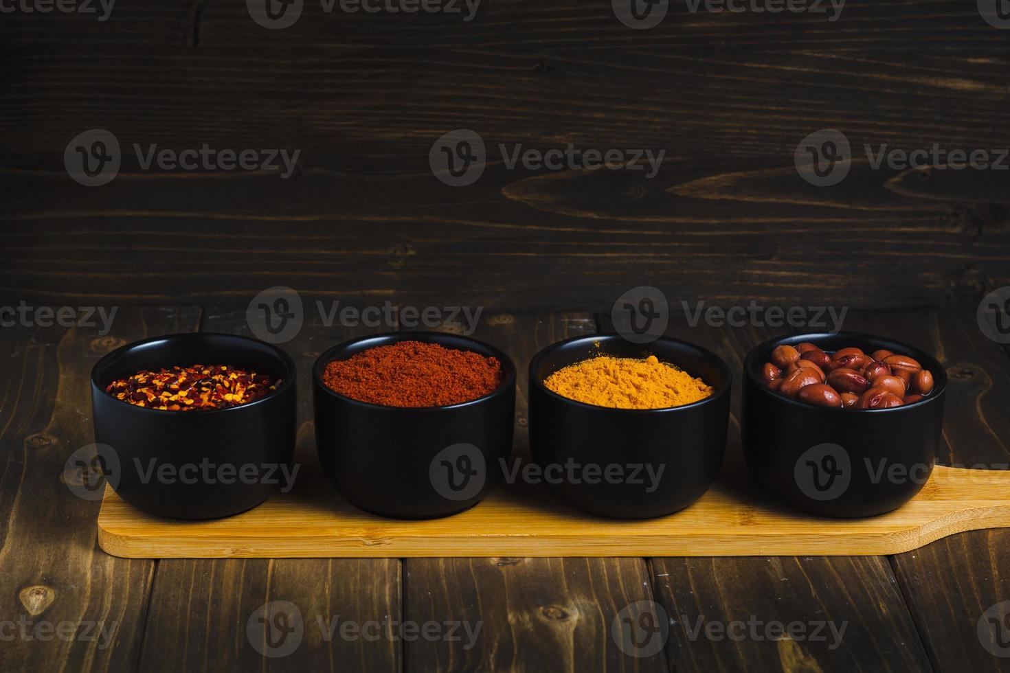 Spices and herbs in ceramic bowls with stand on wooden table photo