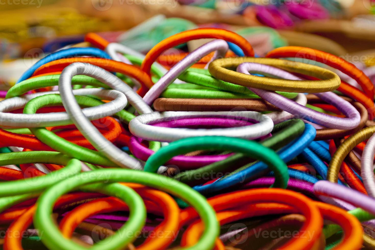 Variety colored handmade bangles are displayed with on some small baskets for sale. photo