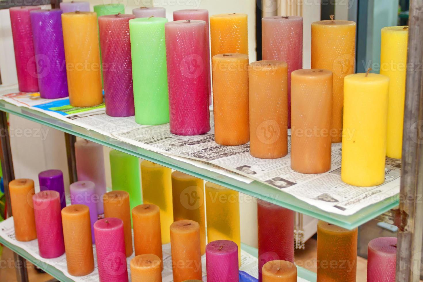 A bunch of unburnt colorful candles are on the display shelf for sale. Unused colorful candles. photo