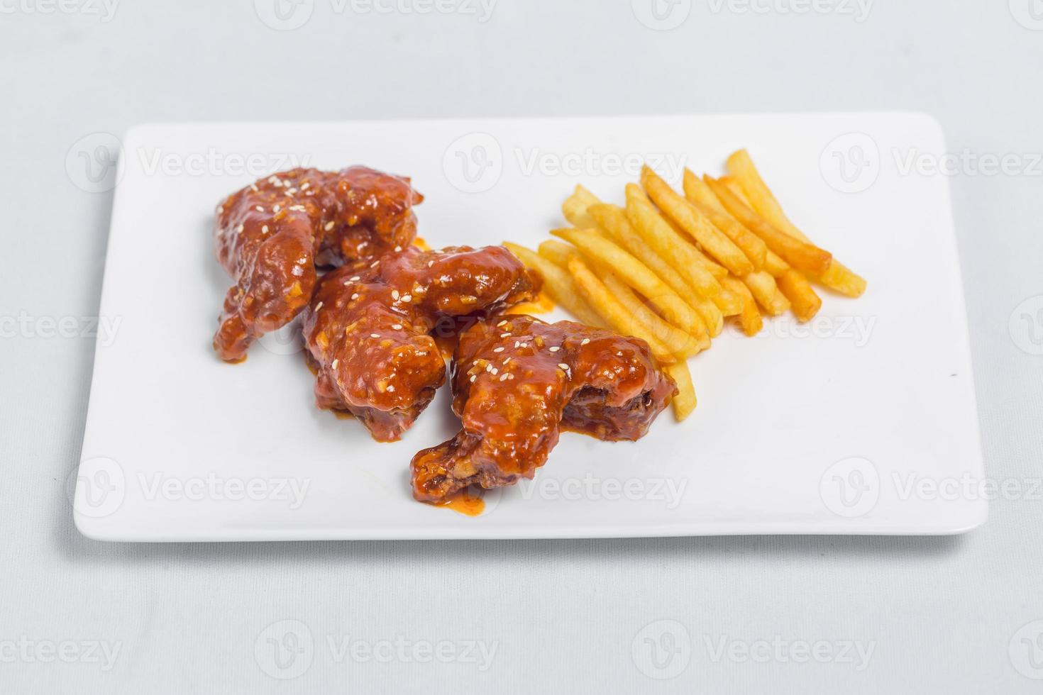 Spicy hot buffalo wings and french fries with white sauce on white plate isolated white background. Top views. photo