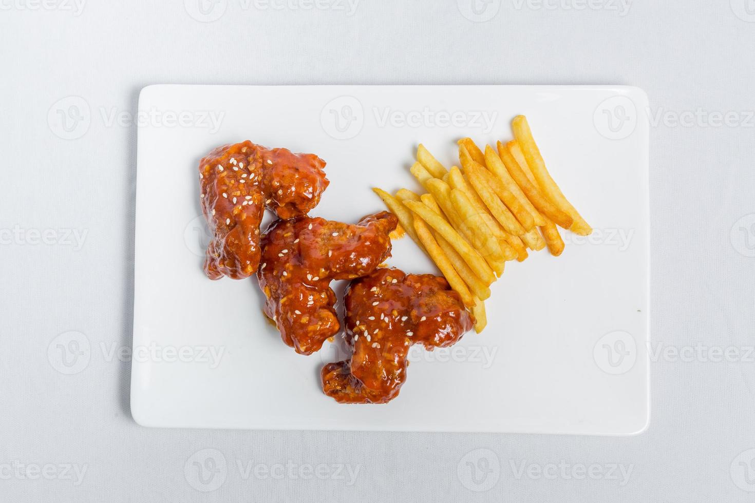 Spicy hot buffalo wings and french fries with white sauce on white plate isolated white background. Top views. photo