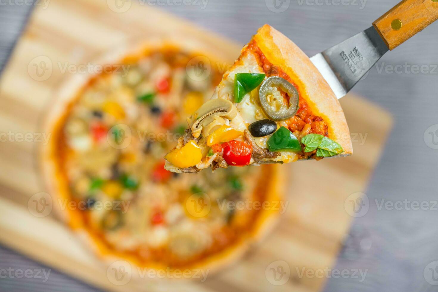 Close up and top view of Chicken mushroom jalapeno pizza slice lifted from wooden cutting board. photo