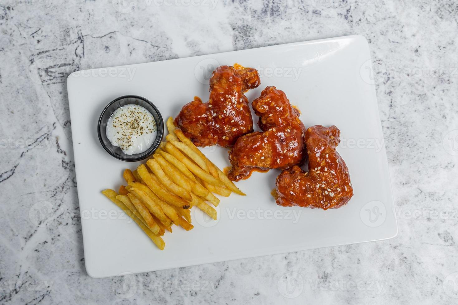 Hot and spicy buffalo chicken wings and crispy french fries with white sauce. photo