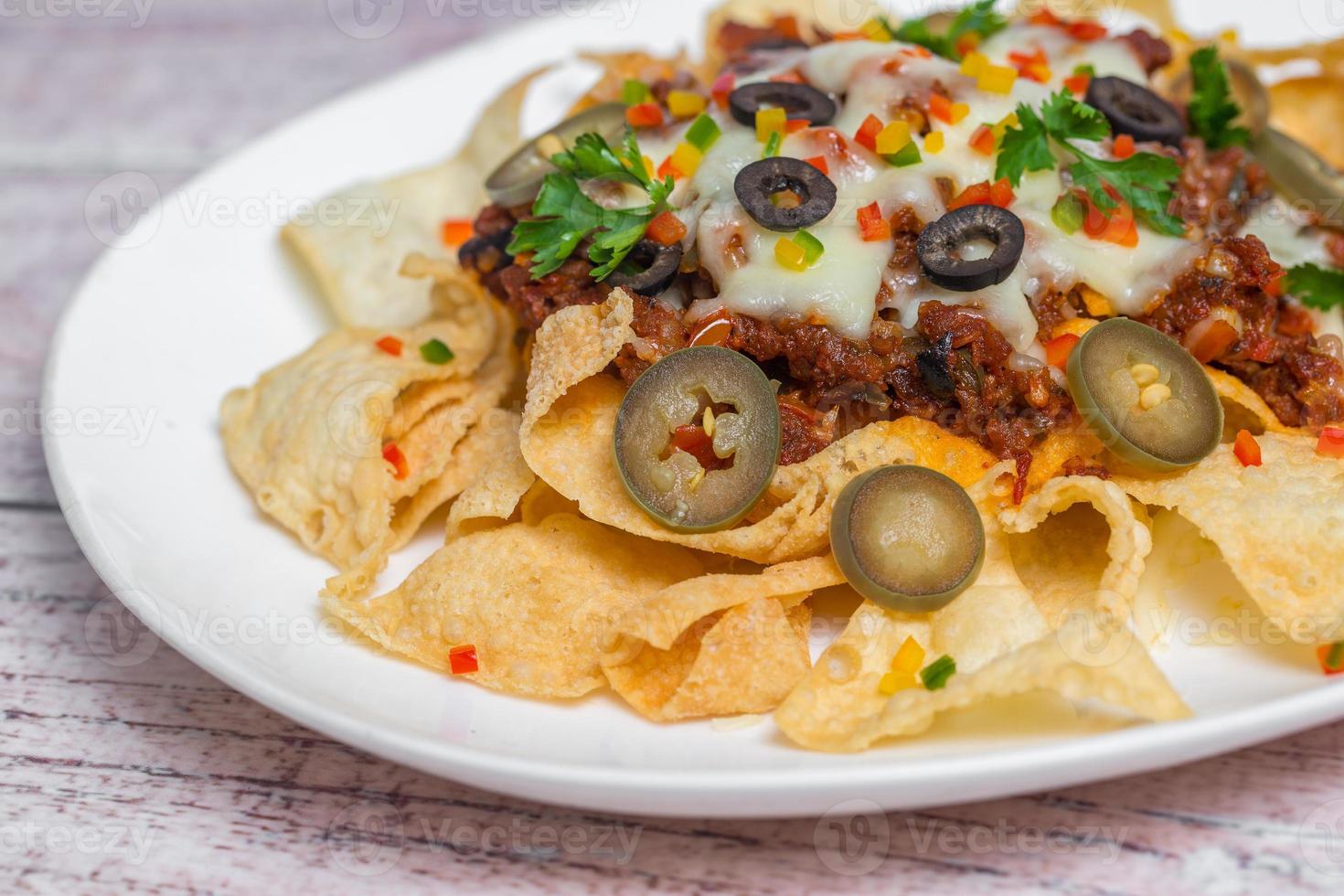 Mexican Famous Food Spicy Ground Beef Nachos. Heated crunchy tortilla chips with melted cheese and jalapeno served a snack food. photo