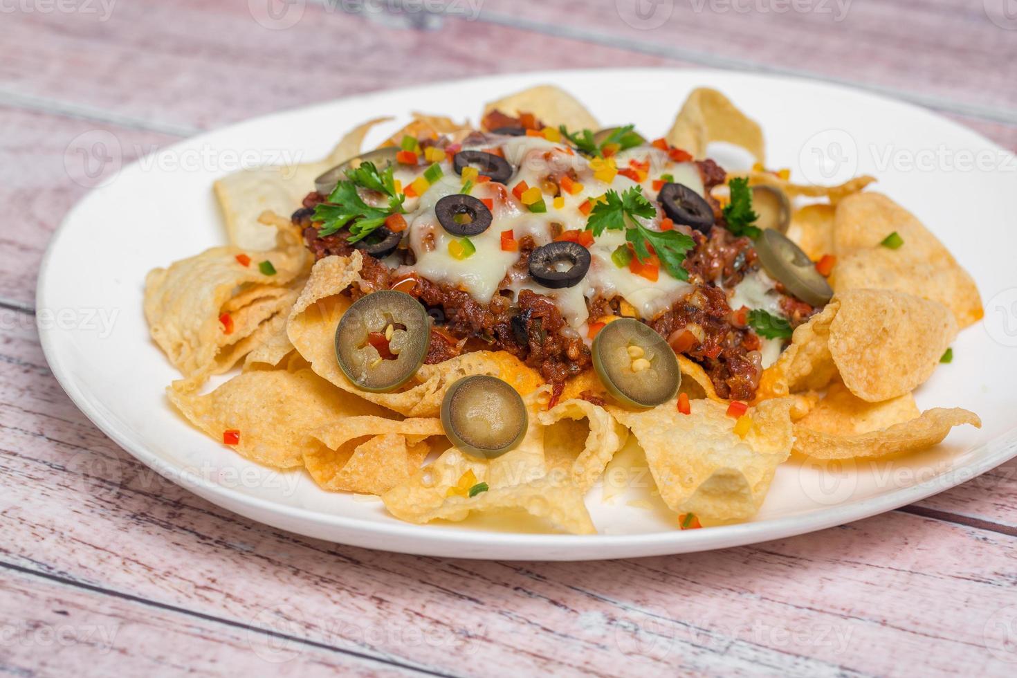 Mexican Famous Food Spicy Ground Beef Nachos. Heated crunchy tortilla chips with melted cheese and jalapeno served a snack food. photo