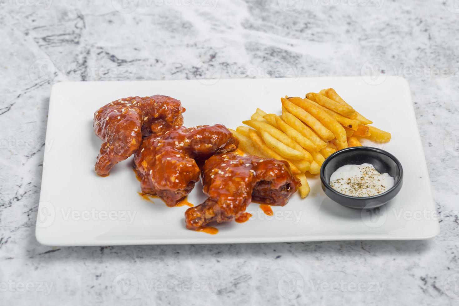 Hot and spicy buffalo chicken wings and crispy french fries with white sauce. photo