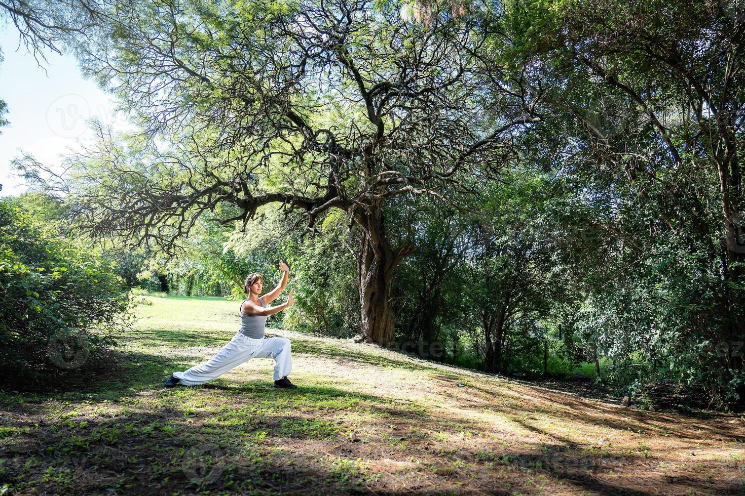 A woman practices Tai Chi in parks. Great general shot. Practicing outdoors provides a calm and relaxing environment for meditation and concentration. photo