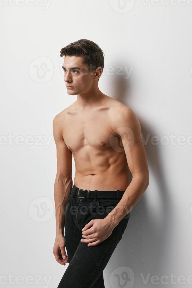Sporty man with a naked torso on a light background and dark trousers model photo