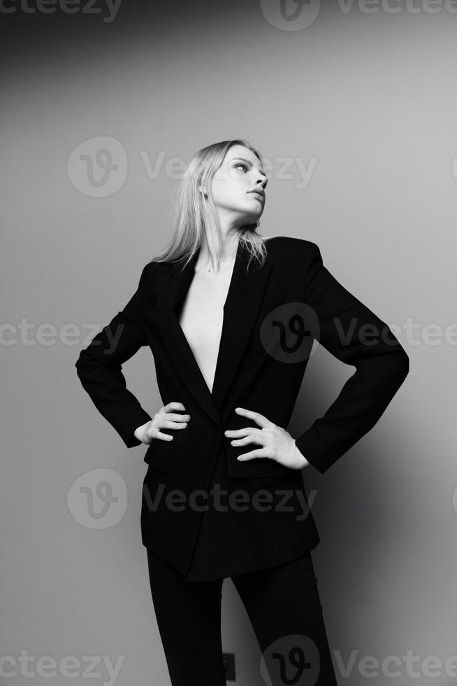 The middle portrait with the legs of a professional model in a classic suit posing with both hands on the waist m looks into the camera photo