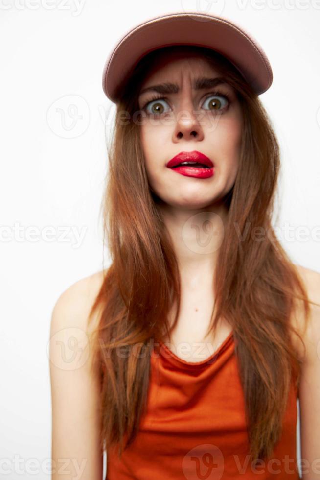 retrato de un mujer en un gorra con un sorprendido mirar, su cara muecas de moda foto