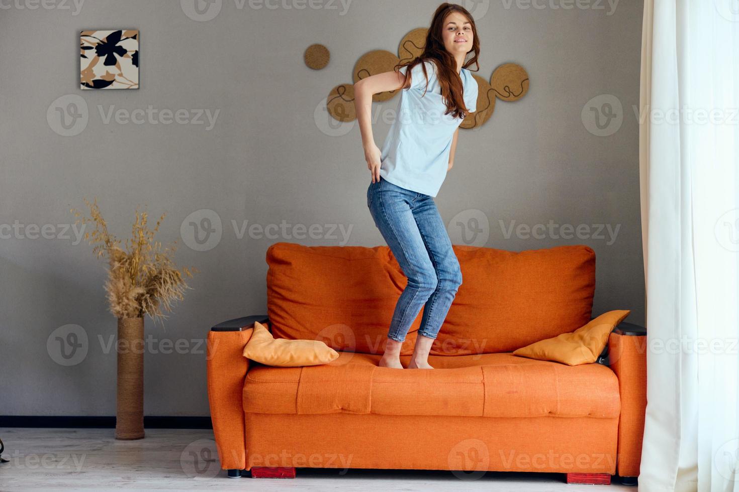 pretty woman in jeans is standing on the couch fun photo