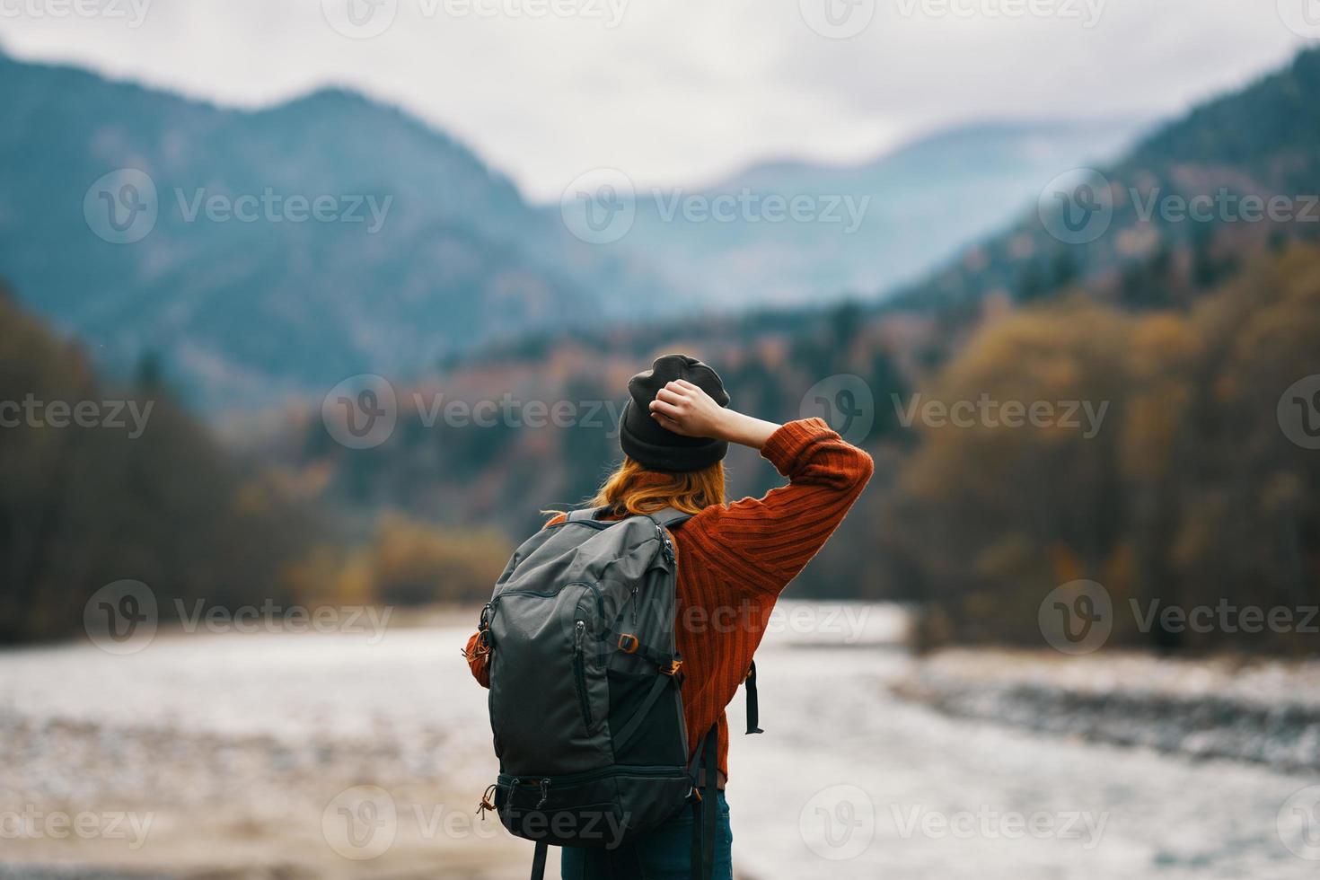 woman on the river bank with backpack travel hiking mountains in the distance photo