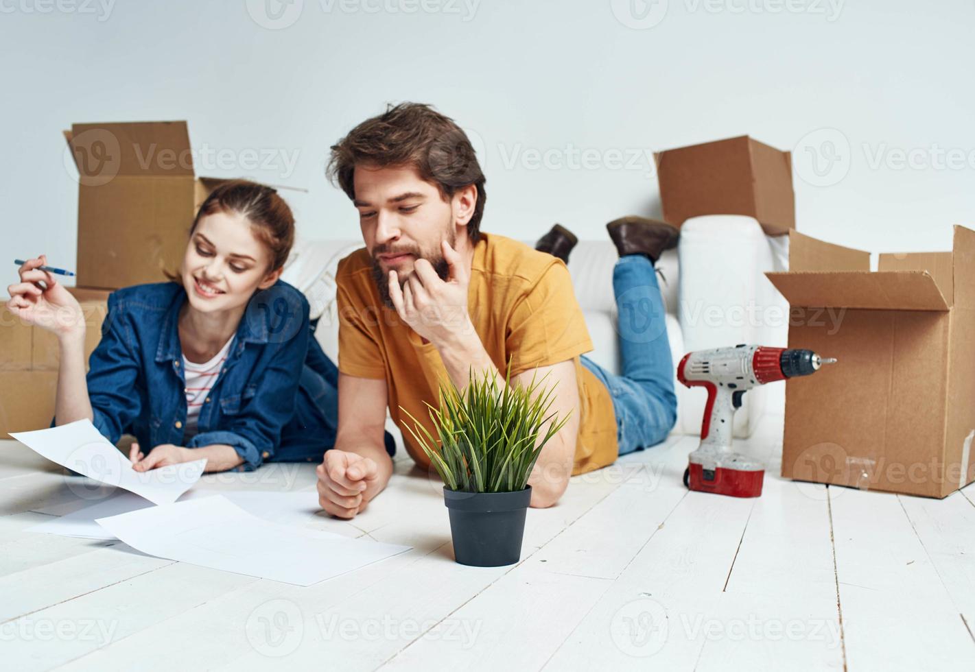 A woman-man with a flower in a pot lie on the floor In a bright room near the sofa photo