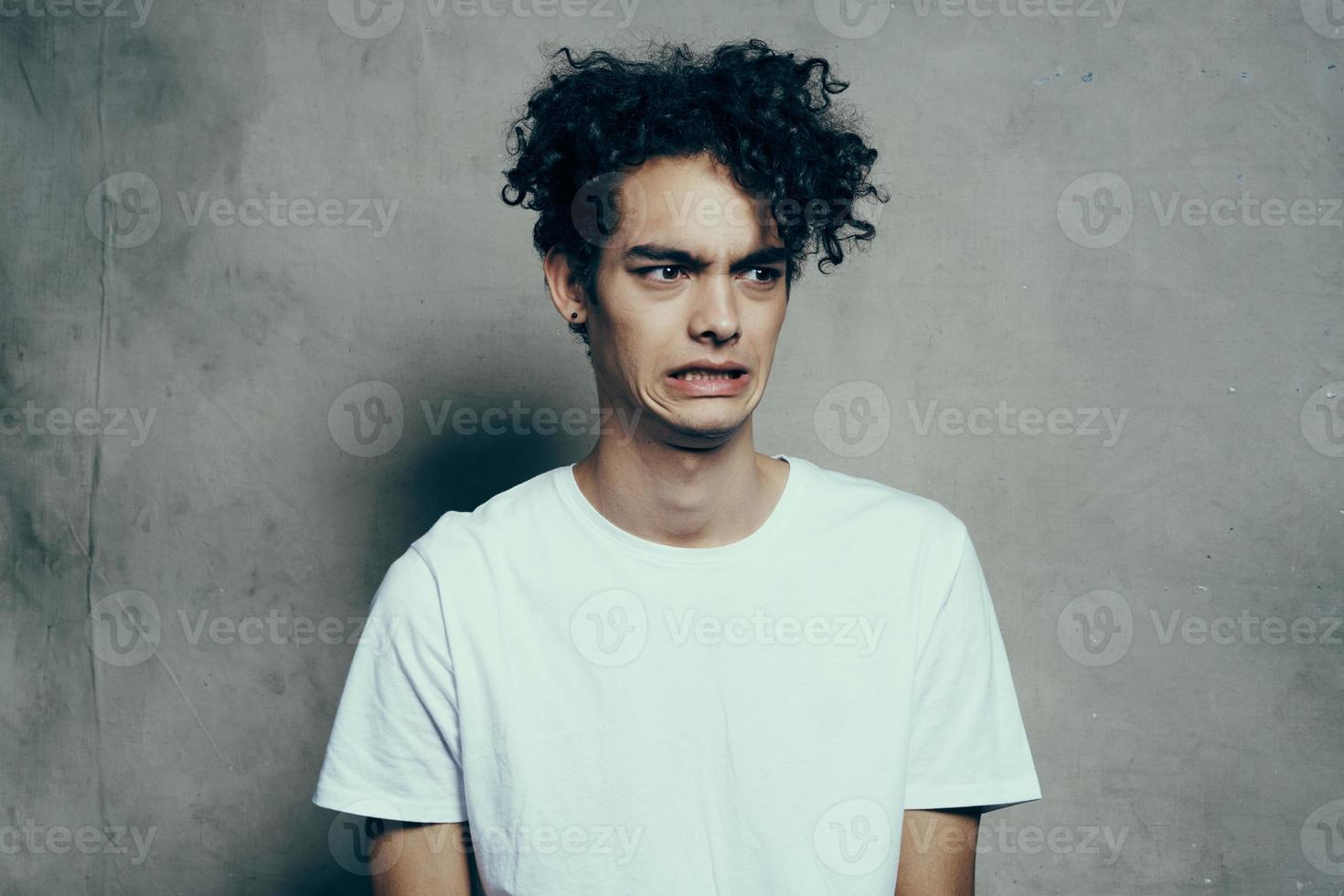 chico con Rizado pelo en un blanco camiseta se sienta en sillas estudio foto