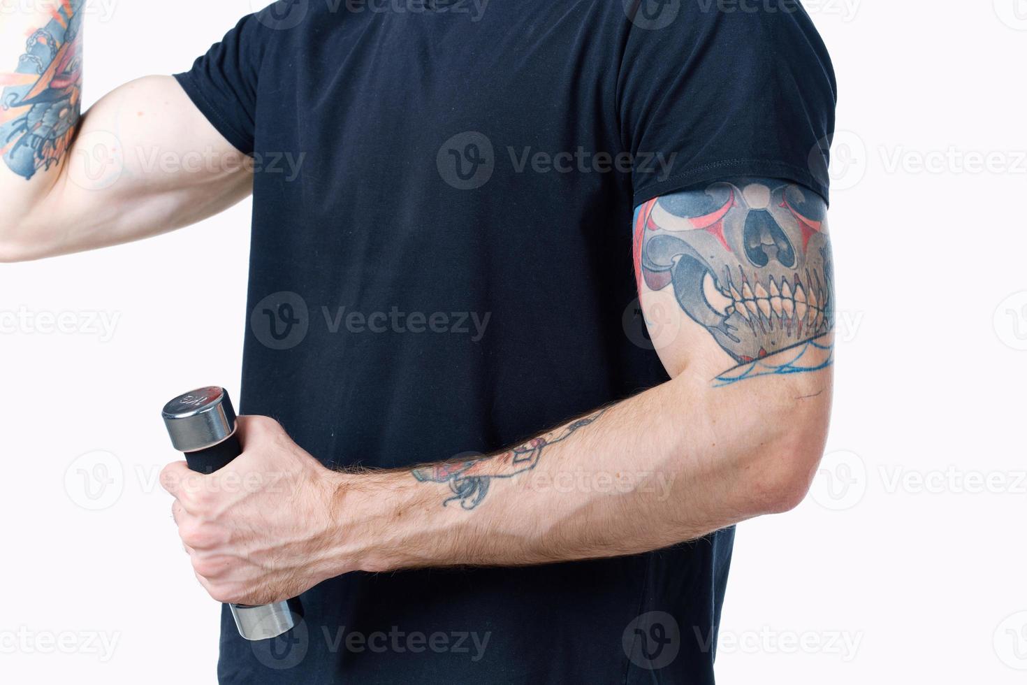 hombre en negro camiseta con tatuaje en su brazo y pesas músculo carrocero foto