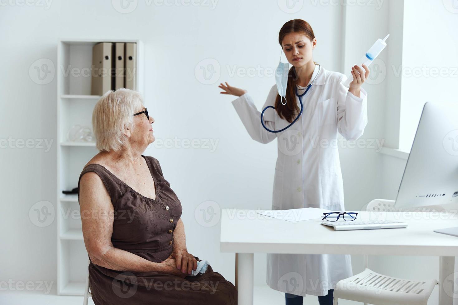 mayor mujer vistiendo un médico máscara en examen por un enfermero médico oficina foto