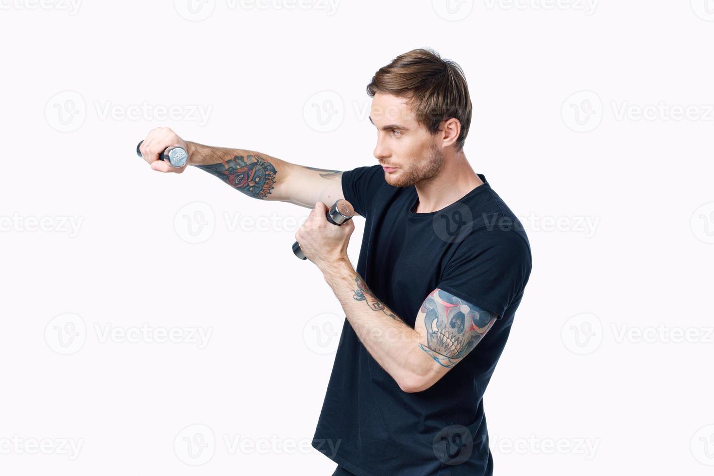 athlete with dumbbells is engaged in fitness on a light background indoors side view photo