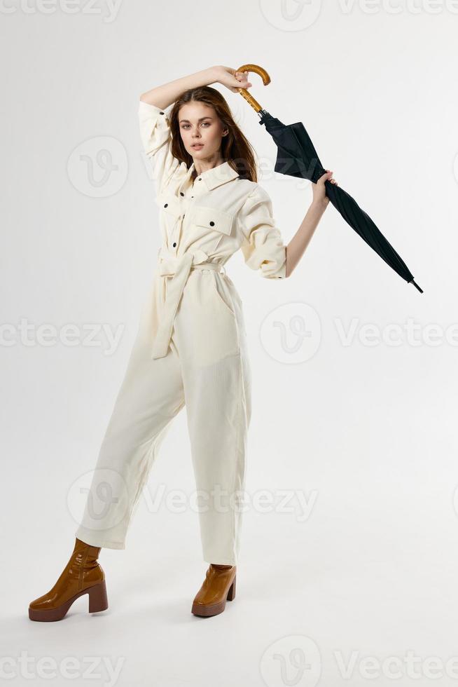 pretty woman in a white jumpsuit with an umbrella in her hands posing in full growth photo