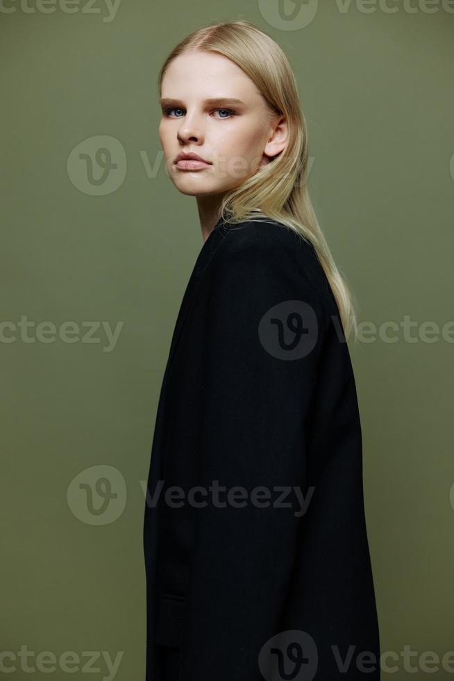 The young model turns and looks at the camera over her shoulder. Cool banner offer. A girl poses in isolation in a suit in a studio with a green background photo