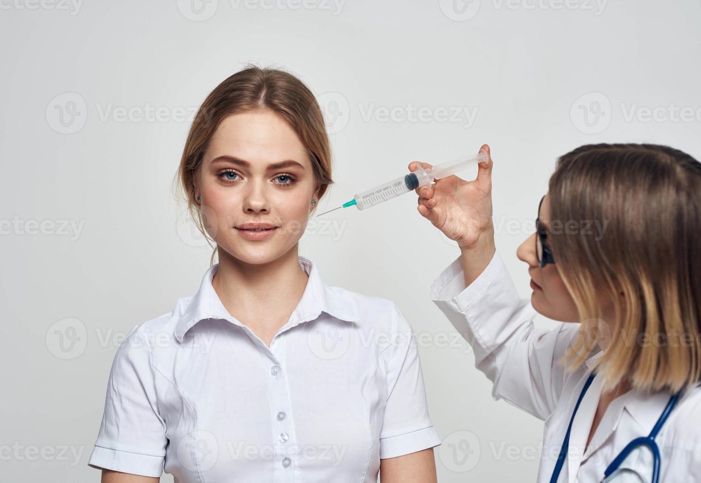 hembra médico muestra el paciente un jeringuilla y un médico vestido un estetoscopio foto