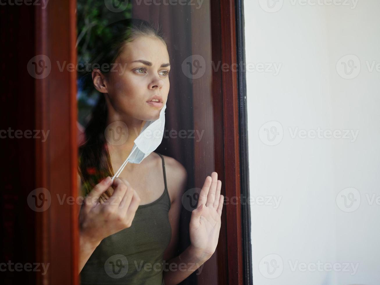 woman in the window wearing a medical mask lockdown ban photo