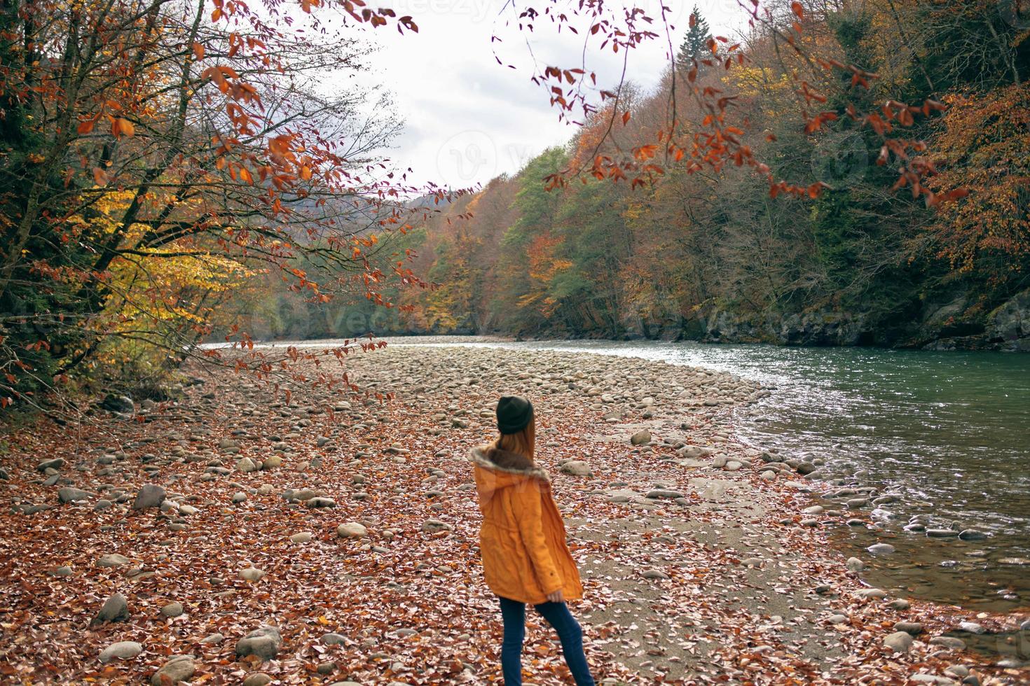 cheerful woman in a yellow jacket near the river autumn walk photo