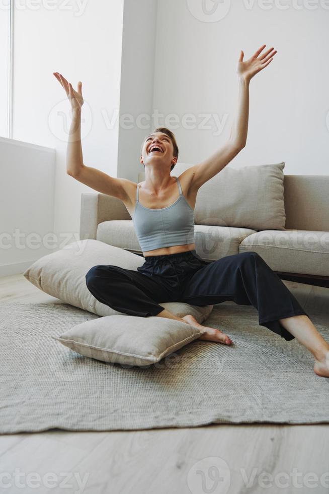 Teenage girl smile everyone sits at home near the couch and tosses up pillows, fun game and happiness without filters, copy place photo