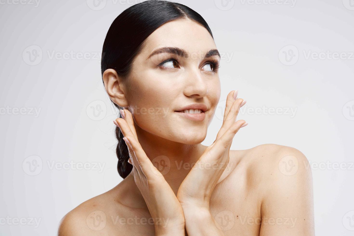 perky brunette with bare shoulders clear skin spa treatments photo