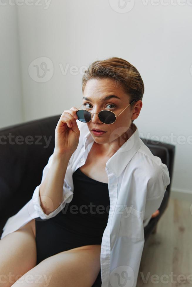 A woman lying on the couch with her glasses on and wriggling photo