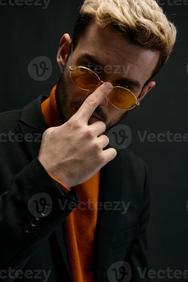 elegante hombres enderezar lentes en cara y naranja suéter modelo negro chaqueta foto