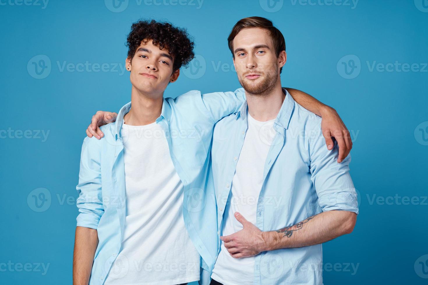 young men in blue shirts hugging on isolated background friends fun photo