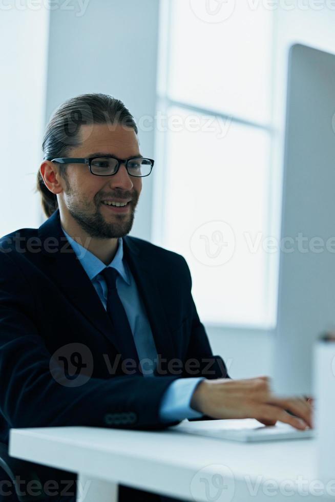 business man in a suit sitting at his desk tired in front of a computer photo