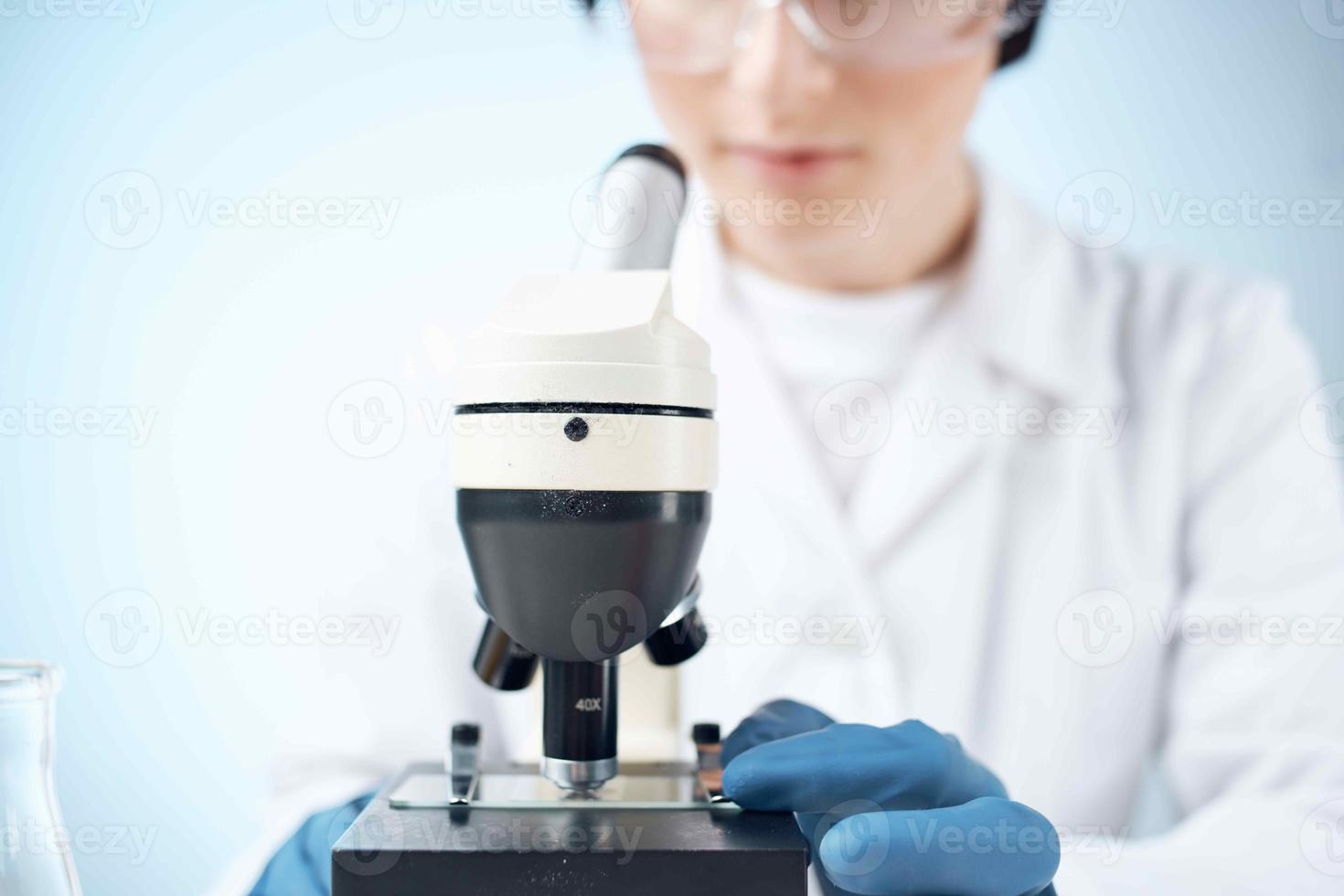 Woman in white coat looking through microscope research technology experiment photo