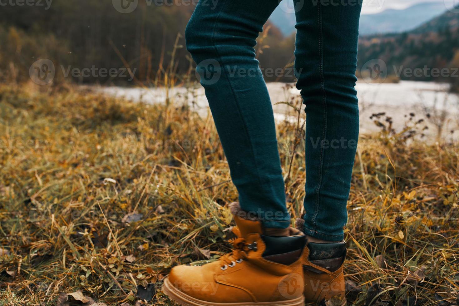 female legs in boots and jeans on nature in autumn in the mountains photo