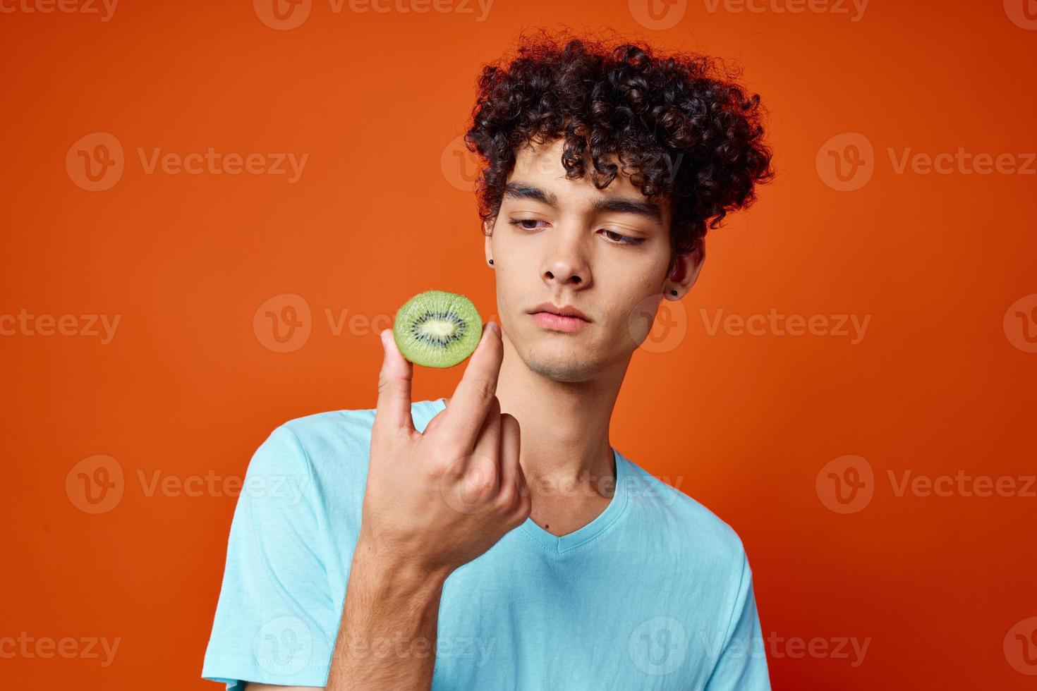 guy in blue t-shirt kiwi holding fruit studio red background photo