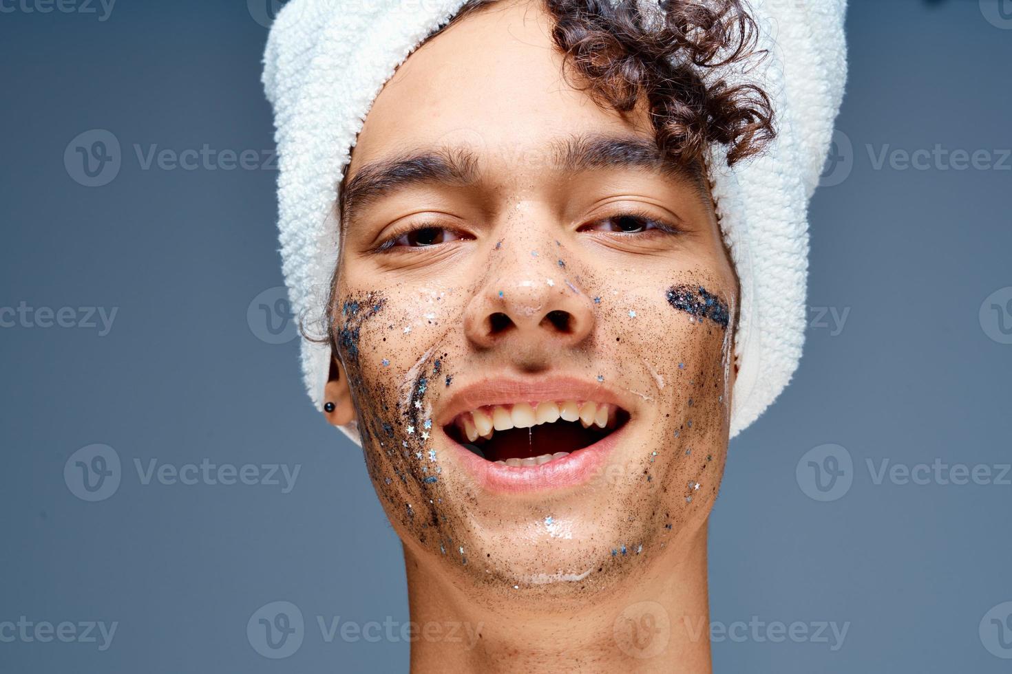 Cheerful guy with bare shoulders with a towel on his head, a black mask on his face photo