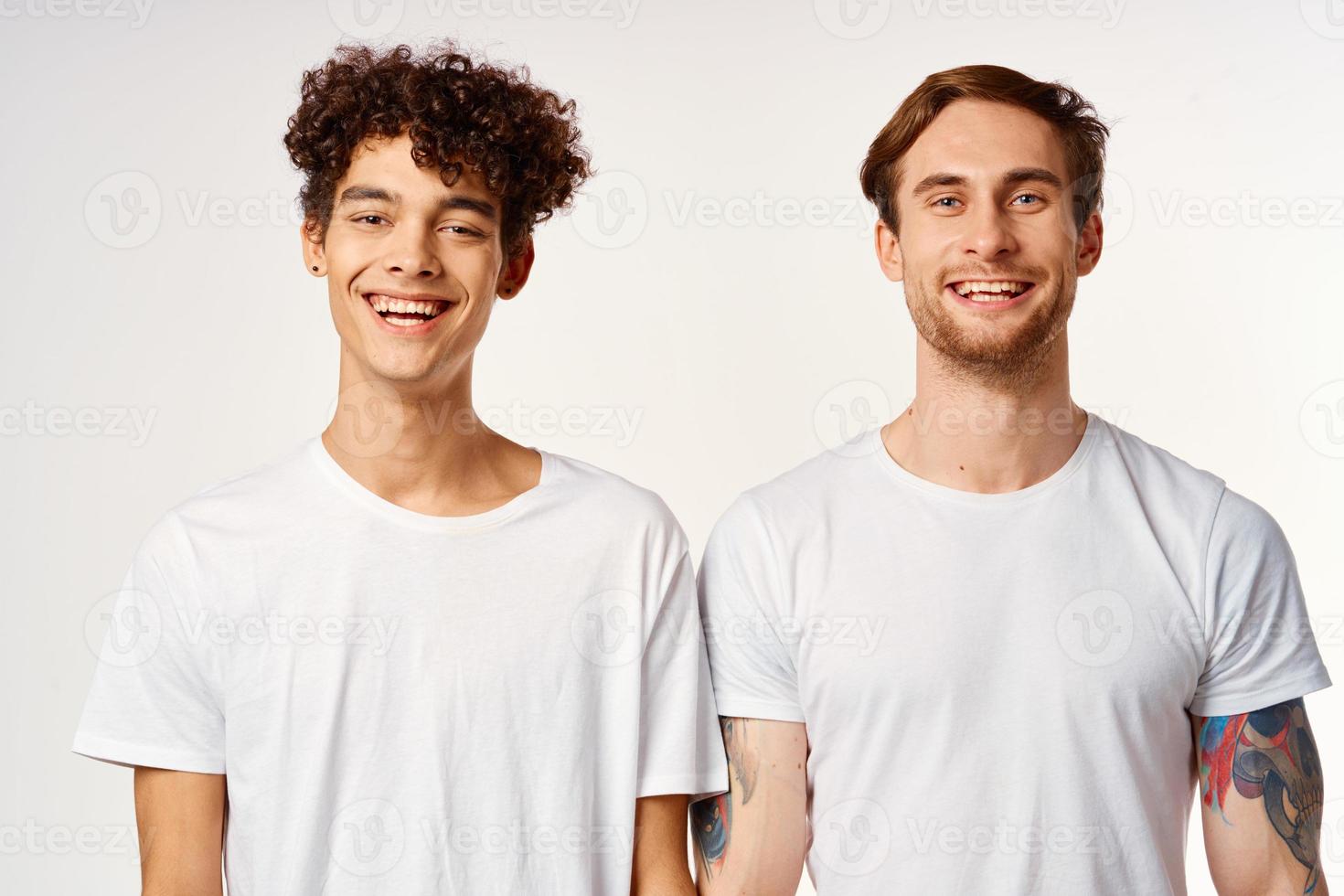Two cheerful friends in white t-shirts emotions studio photo