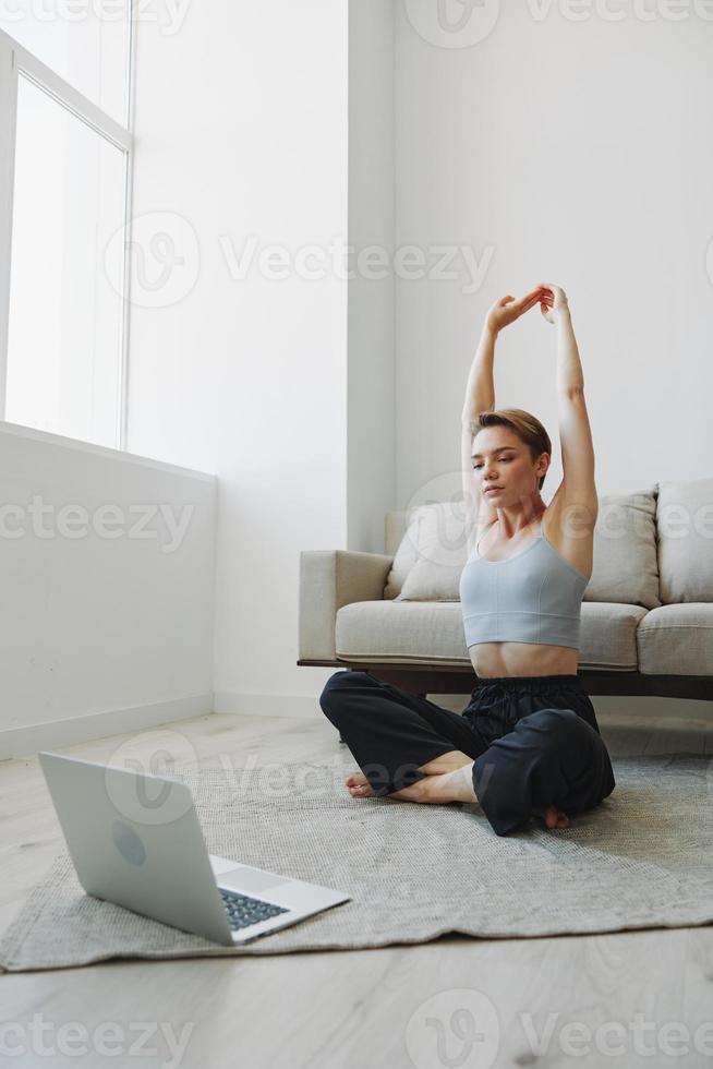 Woman exercising at home by video workout online, meditation and stretching, mental health photo