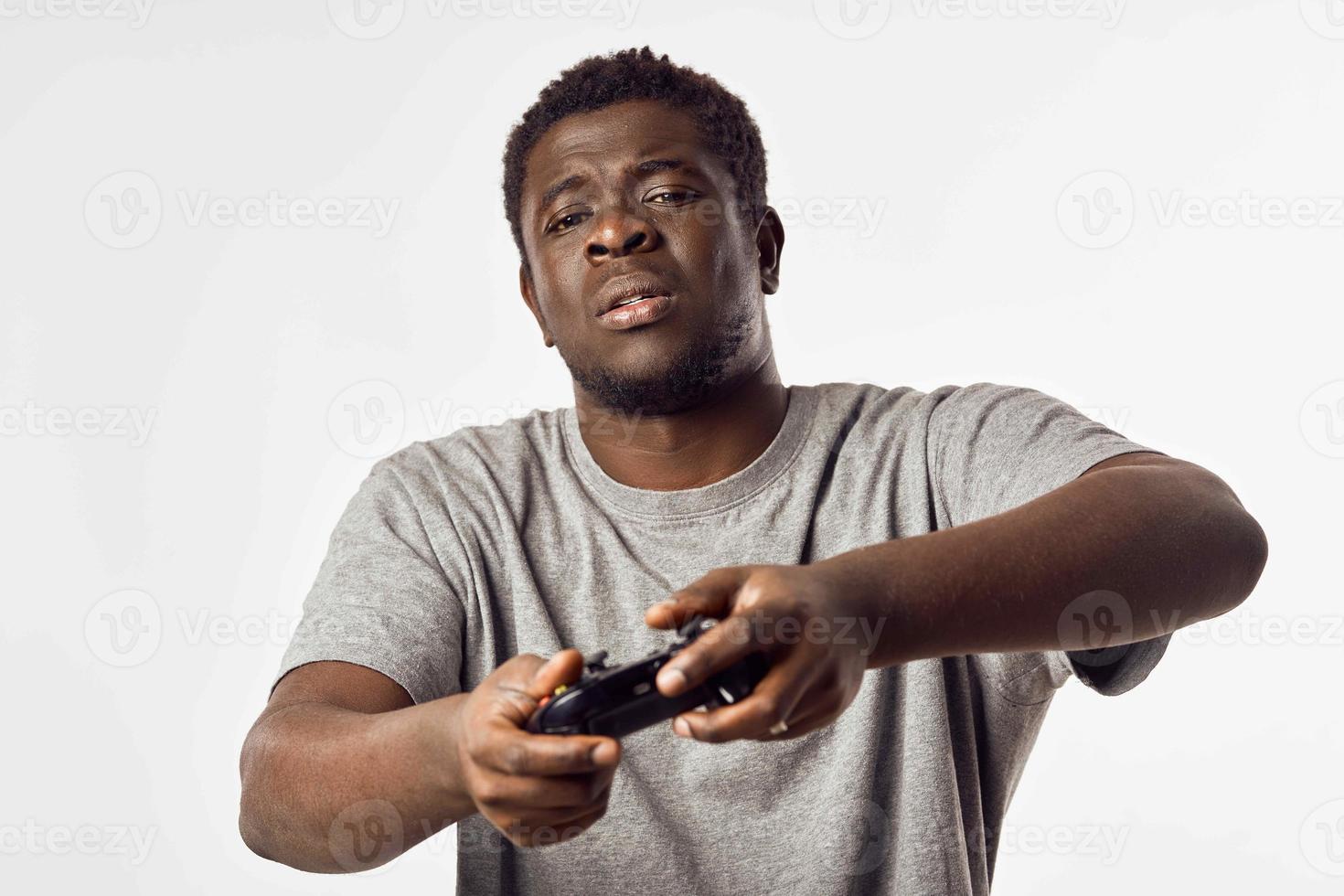 Cheerful man of African appearance with a joystick in his hands plays video games photo