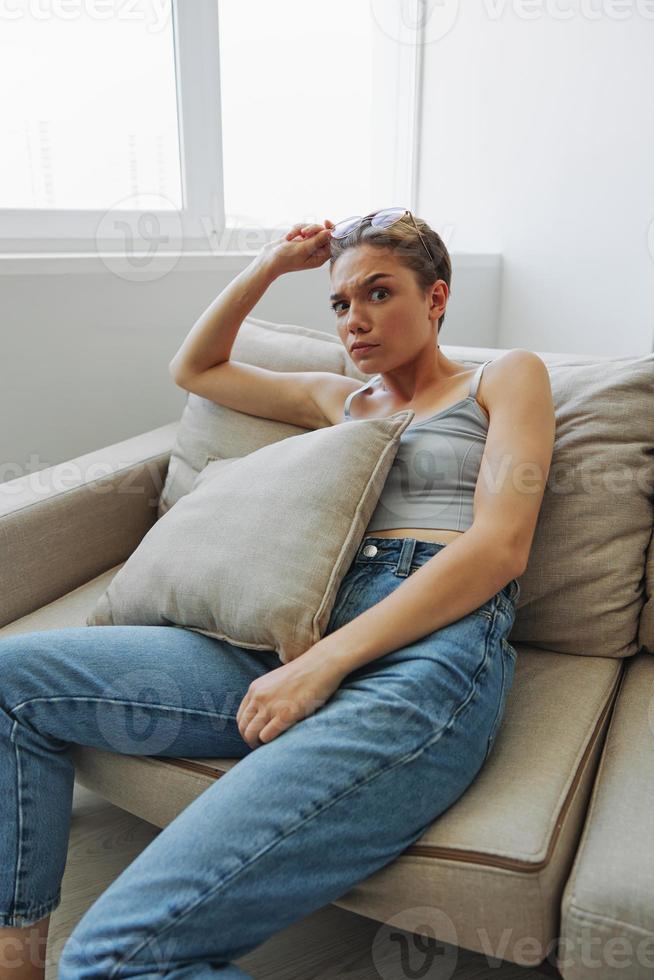 A woman wearing eyeglasses sits on a couch and looks at the camera. Vision problems photo