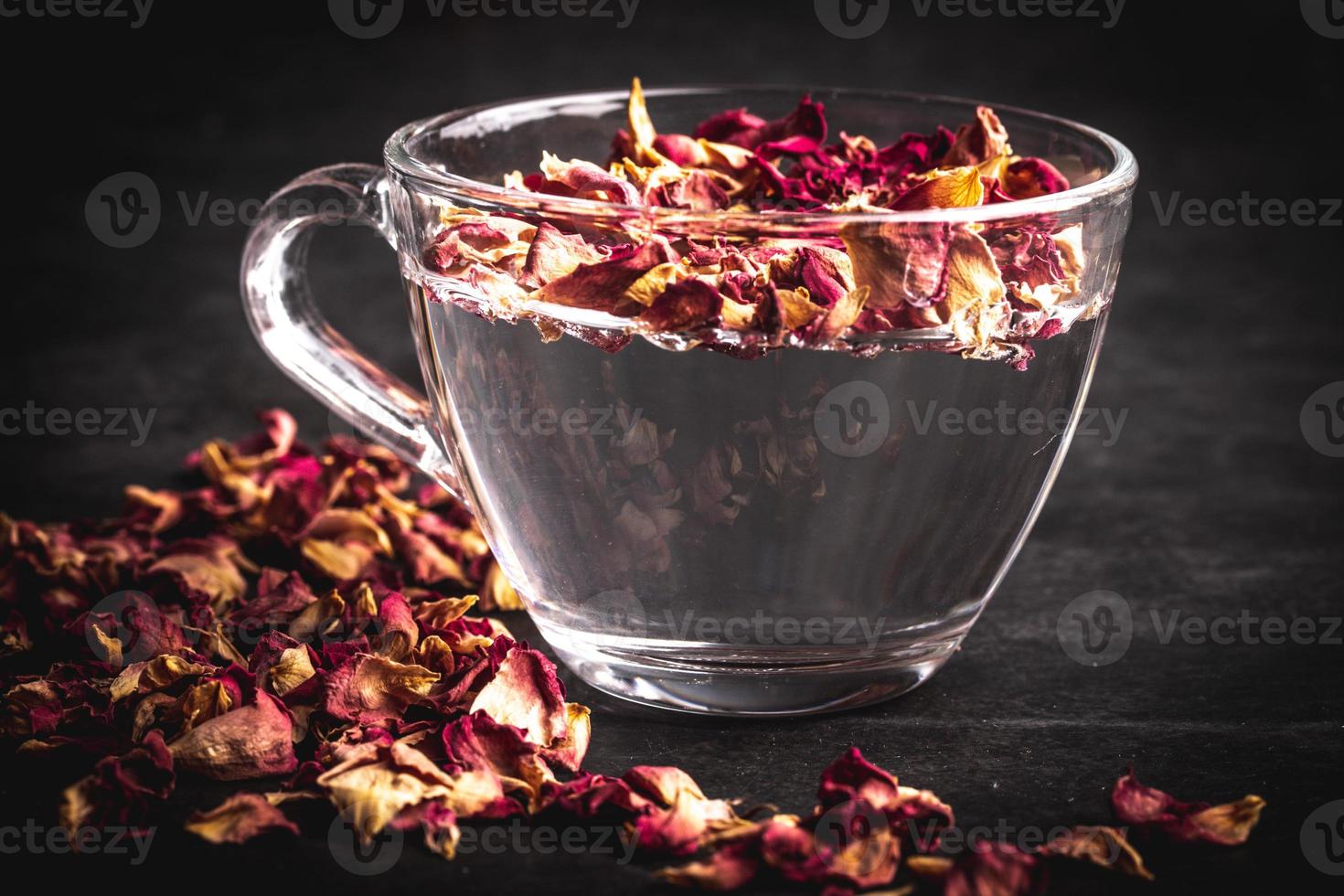 Rose tea in transparent glass on black background photo