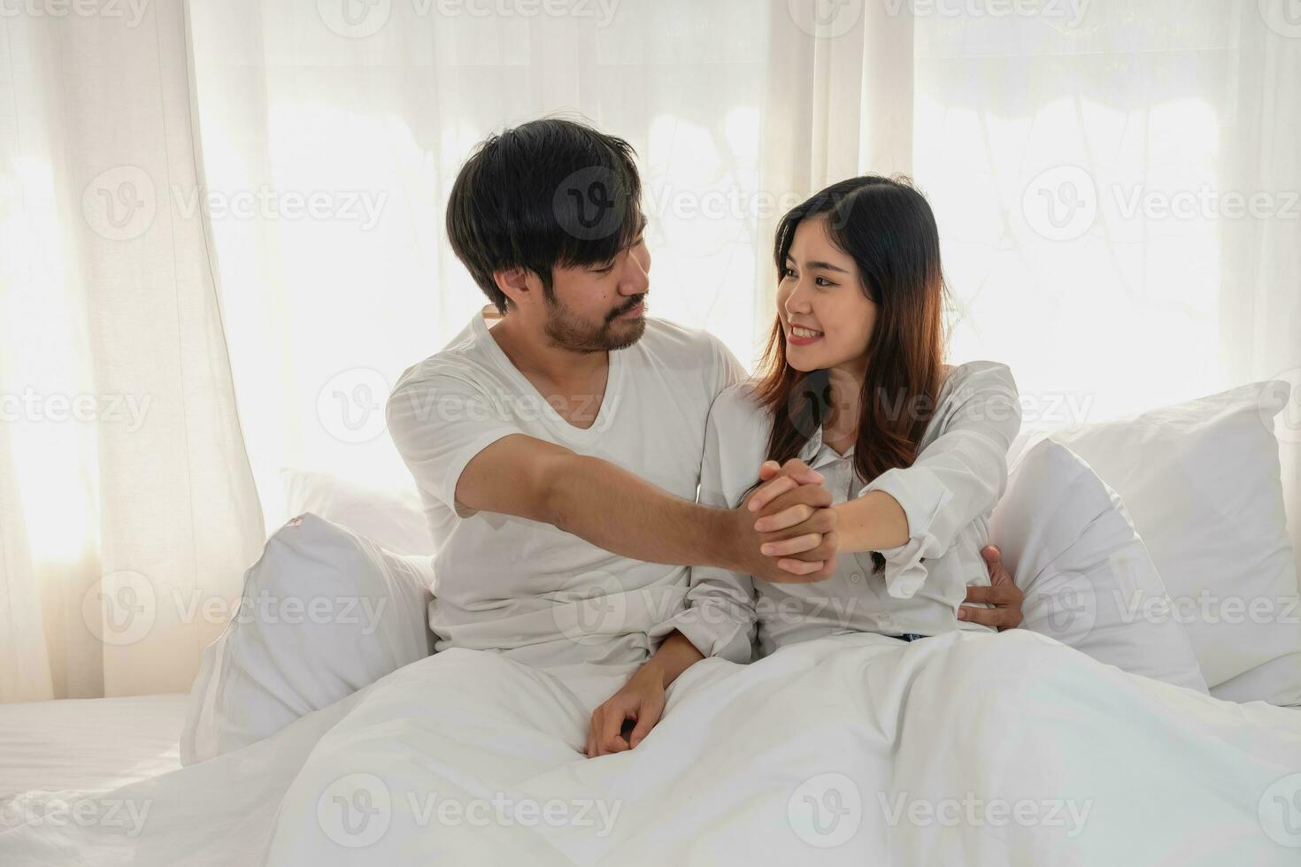 contento joven asiático Pareja abrazando, broma, jugando alegremente en cama a hogar, romántico hora a mejorar familia vinculación familia concepto. foto