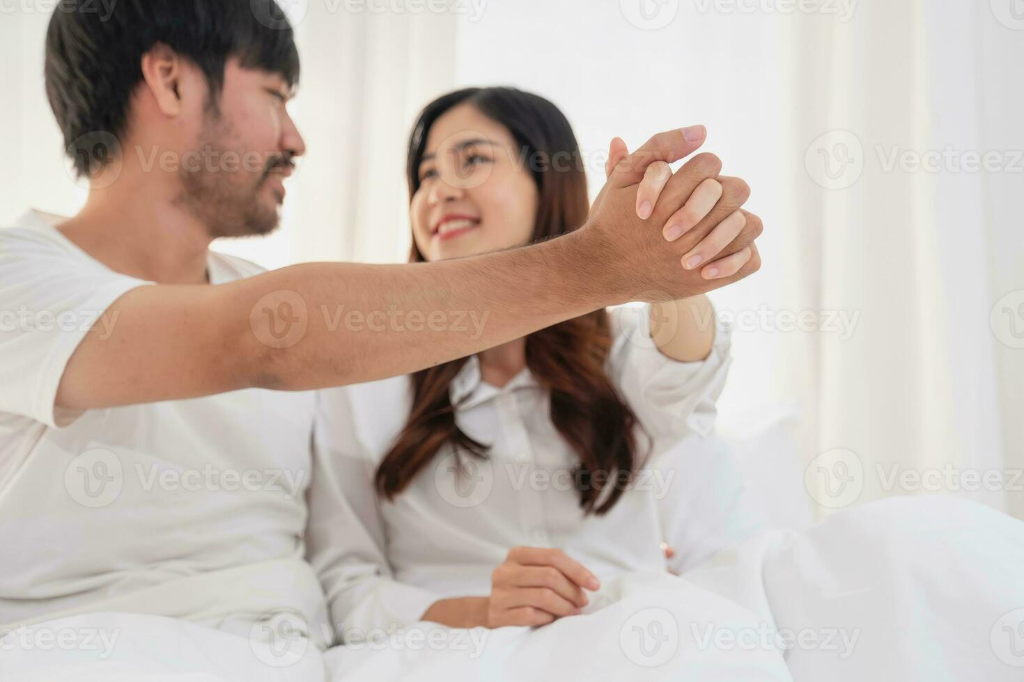 Happy young asian couple embracing, teasing, playing cheerfully in bed at home, romantic time to enhance family bonding. family concept. photo